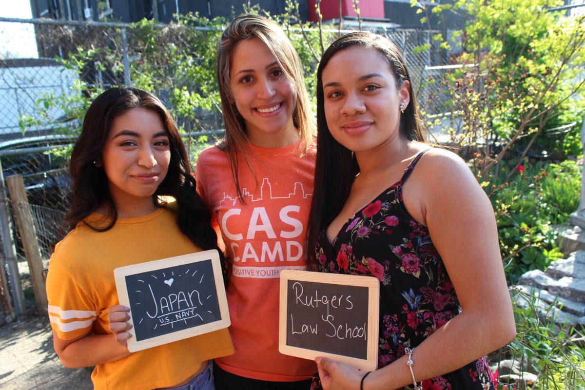 Three girls holding chalkboards with writing on them.