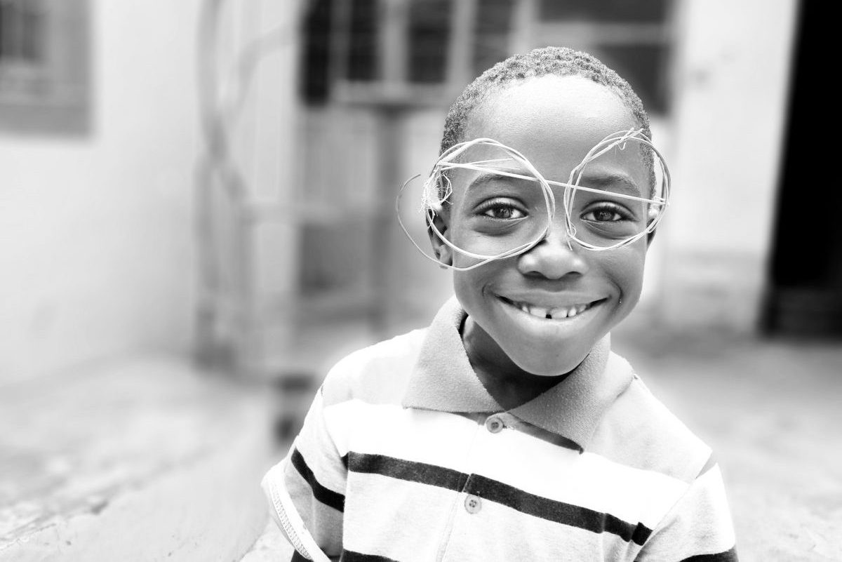 A young boy wearing glasses and smiling for the camera.