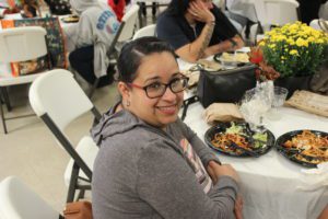 A woman sitting at the table with plates of food.