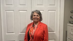 A woman in red jacket standing next to white door.