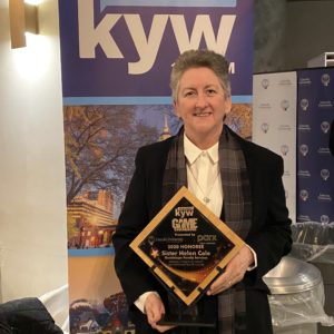 A woman holding an award in front of a kyw sign.