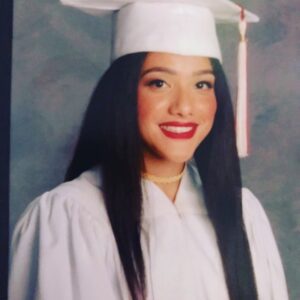 A woman in graduation gown and cap with long hair.