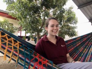 A woman sitting in a hammock smiling for the camera.